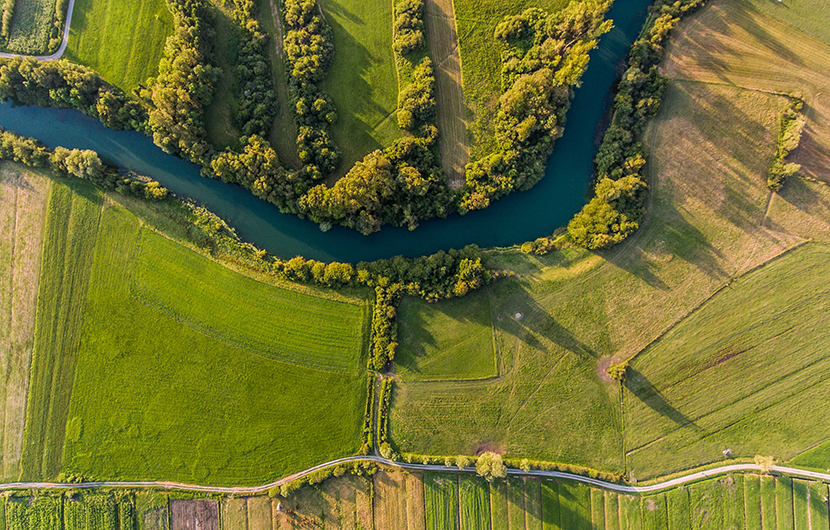 River,Bend,Surrounded,By,Fields,From,Bird's,Eye,View.